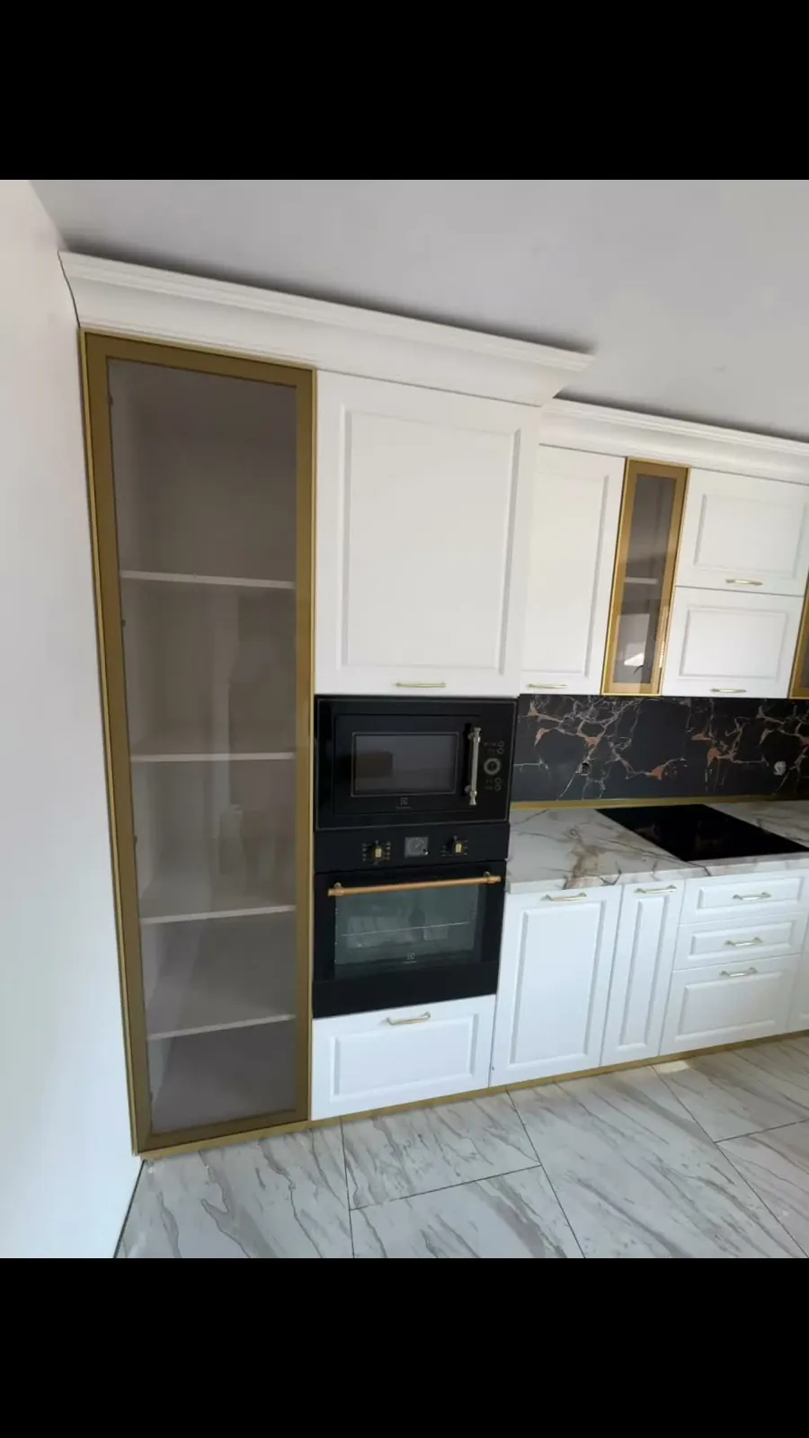 Bucătărie albă clasică cu profile aurii și electrocasnice negre